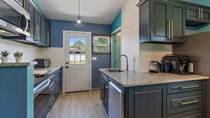 A modern kitchen with dark cabinets, a granite countertop, a built-in oven, and a coffee machine. - Newly renovated, cozy 2 bedroom.  (Englewood)