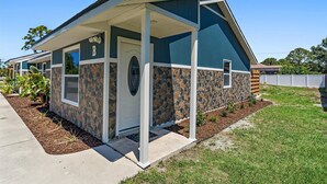 A single-story house with a stone facade, a covered porch, and a well-maintained lawn. - Newly renovated, cozy 2 bedroom.  (Englewood)