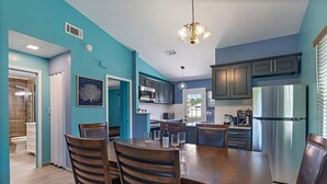 A modern kitchen with dark cabinets, a stainless steel refrigerator, and a dining area with wooden chairs and a table. - Newly renovated, cozy 2 bedroom.  (Englewood)