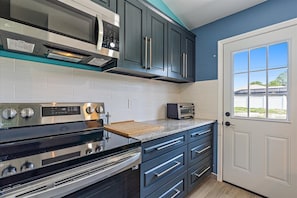A modern kitchen with dark cabinetry, a stainless steel range, a microwave, and a toaster.