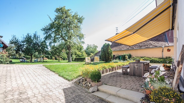 A paved patio with outdoor furniture, a yellow awning, and potted plants. - Vacation apartment "3 Seen" with garden, near Illmensee and Lake Constance (Illmensee)