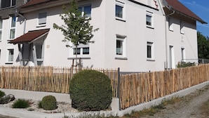 A two-story house with a red-tiled roof, white exterior walls, and a wooden fence. - Vacation apartment "3 Seen" with garden, near Illmensee and Lake Constance (Illmensee)