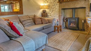 Una sala de estar acogedora con chimenea de piedra, vigas de madera y un sofá cómodo.