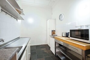 Compact kitchen with stainless steel sink, microwave, and oven, along with white cabinetry and a refrigerator.