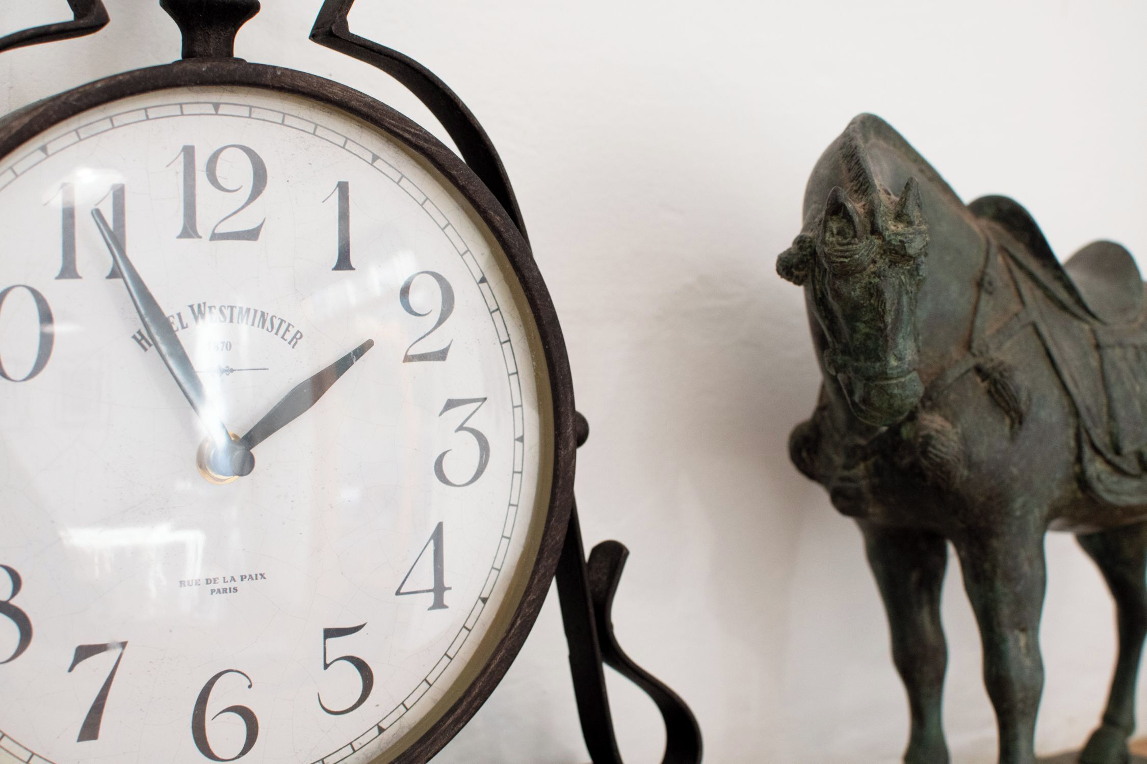 A clock with Roman numerals and a statue of a horse.