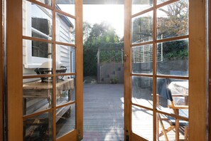 A wooden deck with a view of a white building and a metal gate.