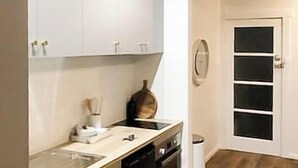 Uma cozinha moderna com armários brancos, uma máquina de lavar louça e piso de madeira.