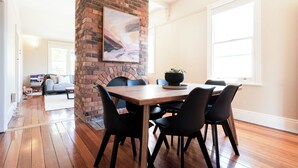 Un coin repas avec une cheminée en briques, une table en bois et des chaises noires.
