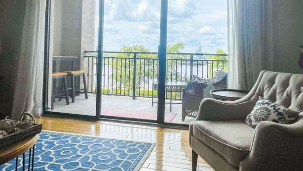 A living room with a sofa, a coffee table, and a view of a balcony with outdoor furniture. - Riverfront balcony  WSR #10 (Wilmington)