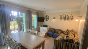 A compact living space with a dining area, a kitchenette, a sofa, and a TV.