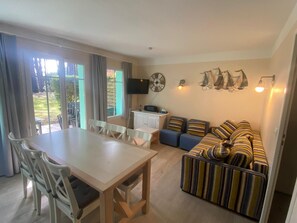 A compact living space with a dining area, a kitchenette, a sofa, and a TV. - Nice house in residence with large swimming pool (Lacanau)