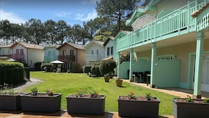 A courtyard with a green lawn, potted plants, and a building with a balcony.