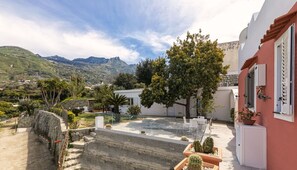 A courtyard with a stone staircase, potted plants, and outdoor furniture. - Iris House (Forio)