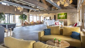Een ruime lobby met een pooltafel, zithoeken en een receptiebalie.