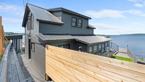 A two-story house with a large deck and a view of the water. - Lakeside Cottage ~ Pool, Hot tub & Private Beach (Colchester)