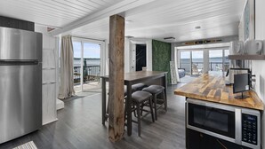 A modern kitchen with a wooden bar, stainless steel appliances, and a view to the outside. - Lakeside Cottage ~ Pool, Hot tub & Private Beach (Colchester)