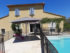 A building with a pool, outdoor seating, and a covered patio area. - Villa with a private pool (fenced) and a pétanque court – Mont Ventoux – Last-minute offer (Modène)