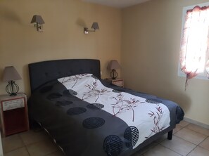 A bedroom with a bed, two bedside lamps, a nightstand, a window with curtains, and a wall-mounted lamp. - Villa with a private pool (fenced) and a pétanque court – Mont Ventoux – Last-minute offer (Modène)