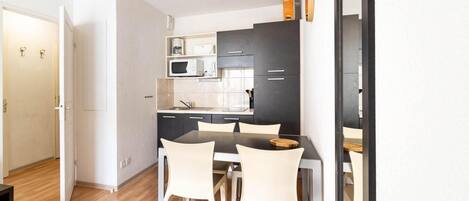 A compact kitchen with a dining area, featuring a microwave, stove, and cabinets.