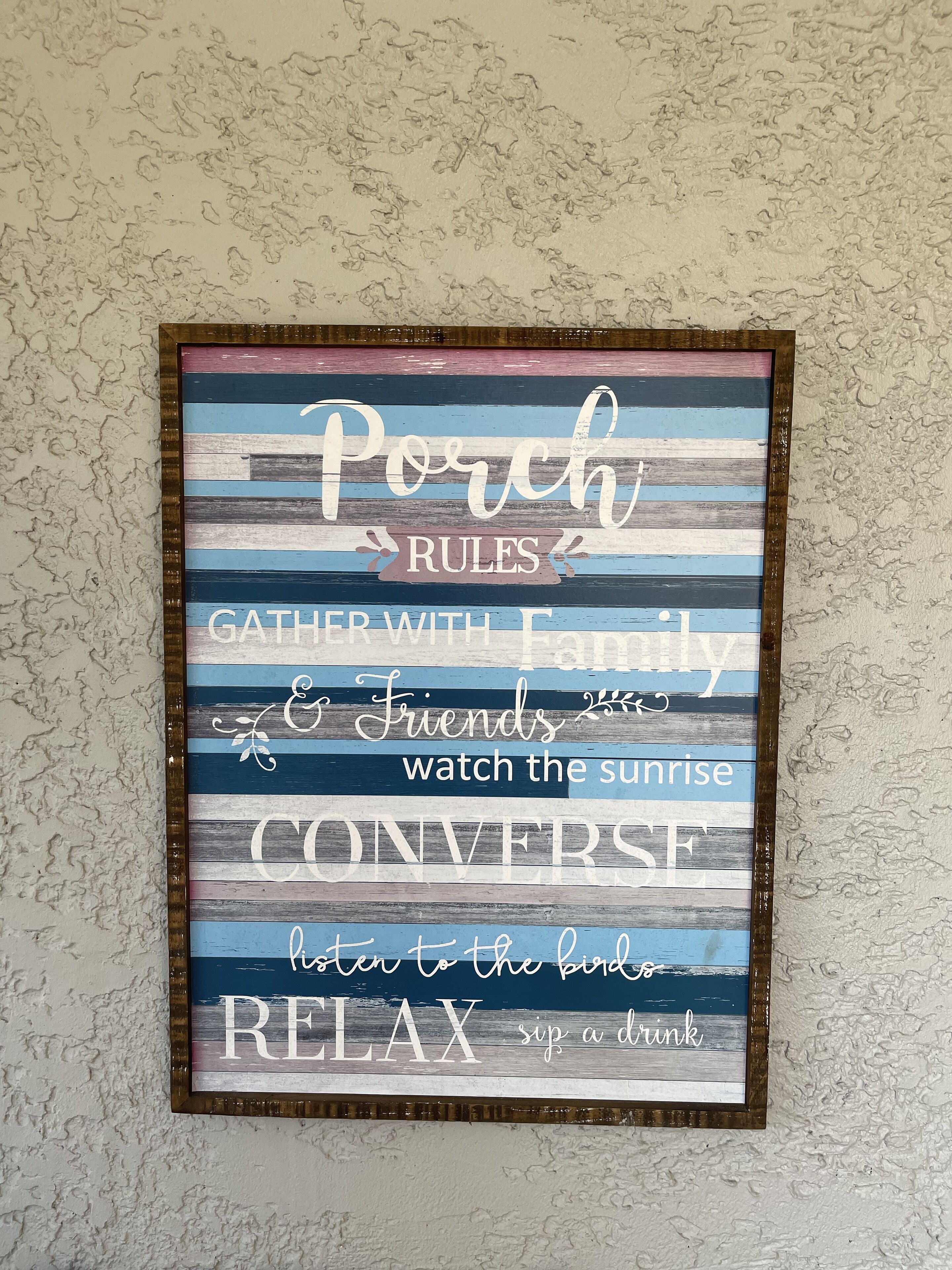 A framed sign with 'Porch Rules' and various activities like gathering with family, watching the sunrise, conversing, listening to birds, and relaxing with a drink.