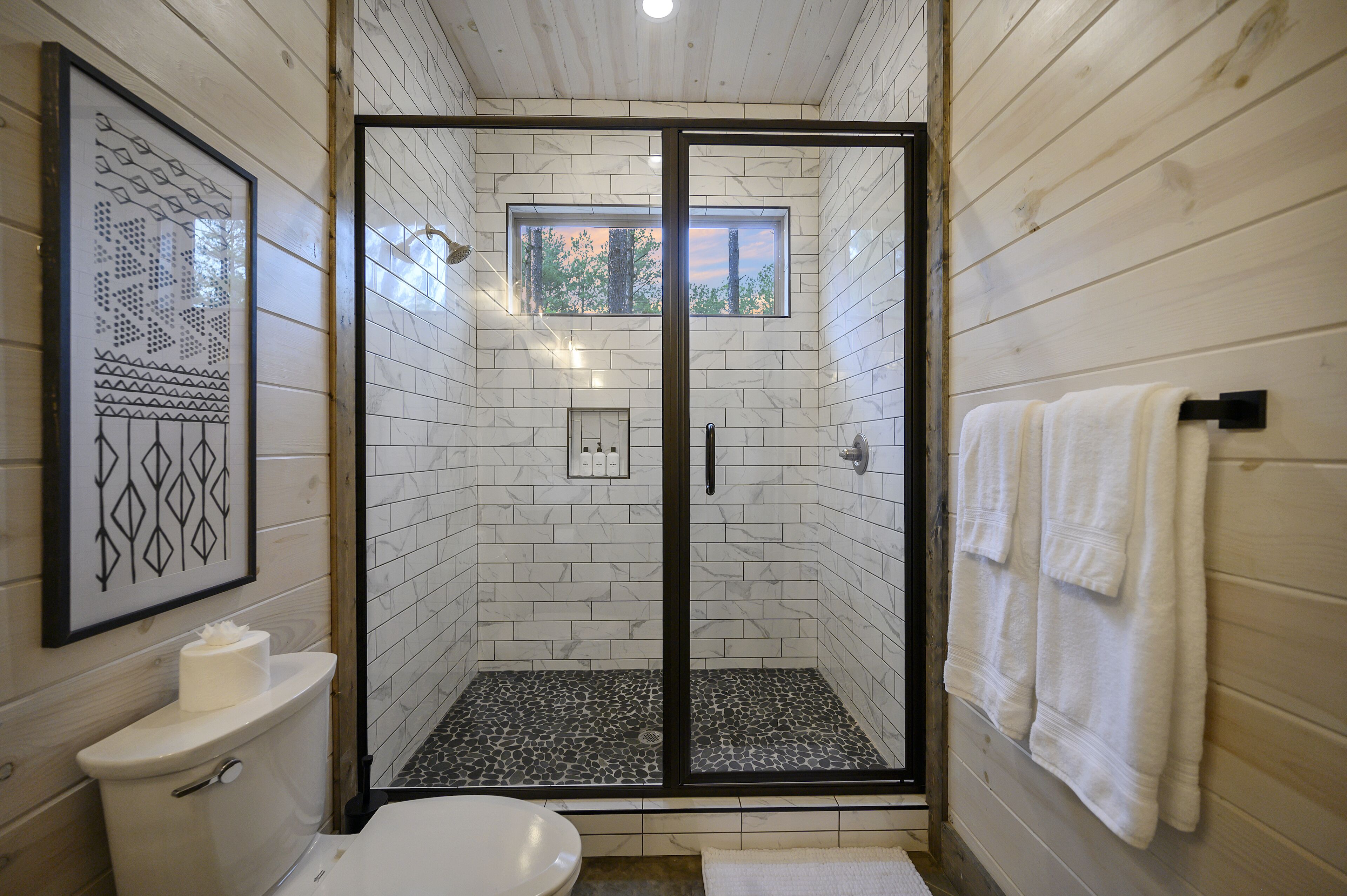 A bathroom with a glass-enclosed shower, a toilet, and a sink.