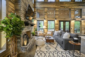 Un salón amplio con chimenea de piedra, ventanas grandes y una zona de estar acogedora.