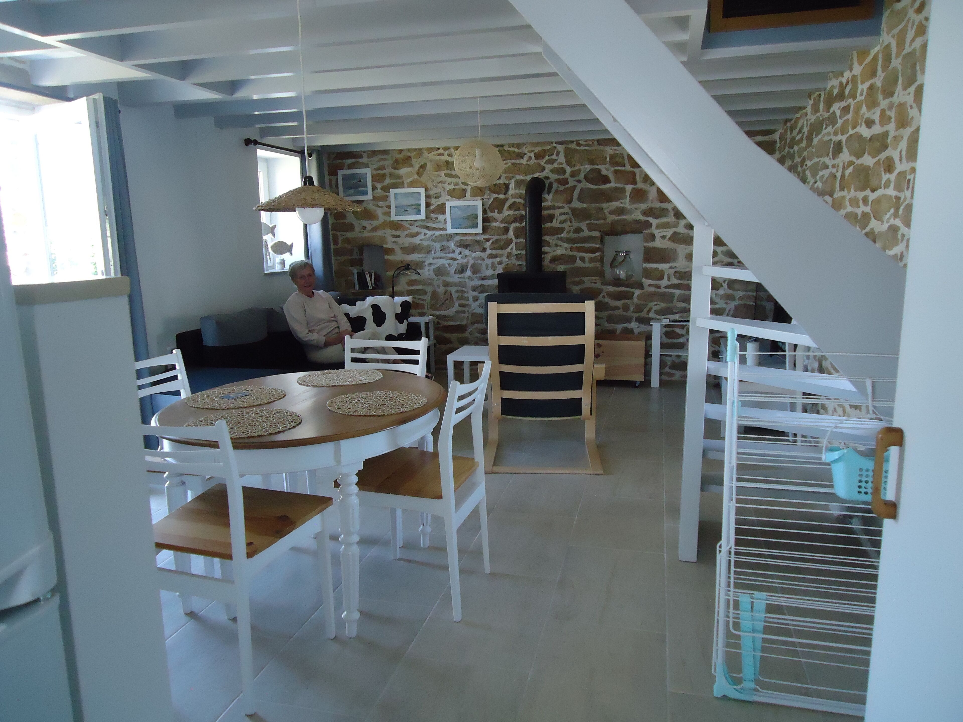 A dining area with a round table and chairs, a stone wall, and a staircase.