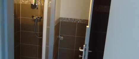 Un baño pequeño con cabina de ducha, inodoro y lavabo.