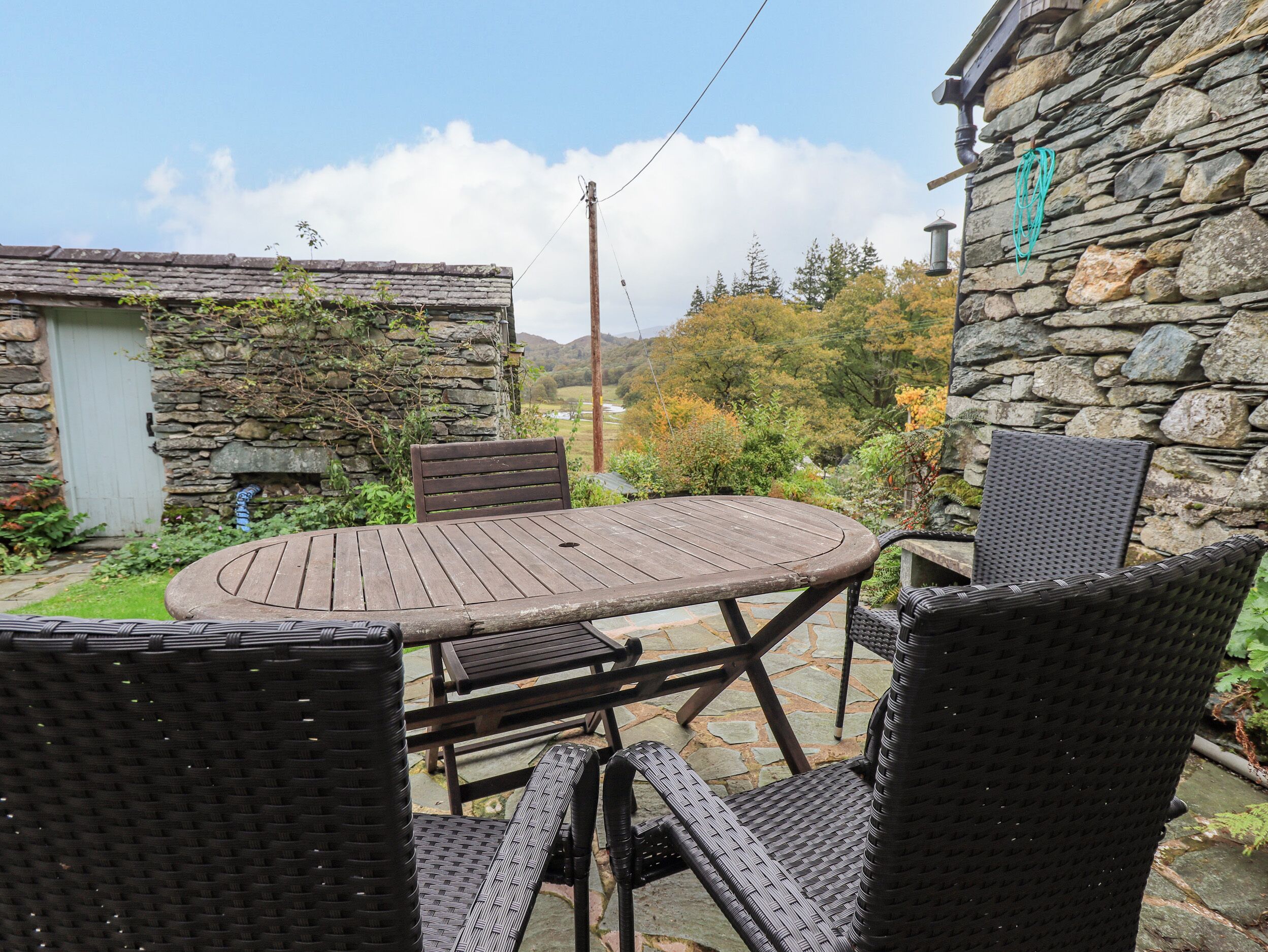 An outdoor patio with a round wooden table and four wicker chairs.