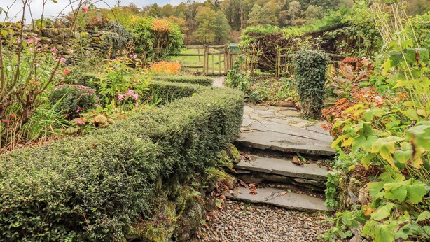 Ein Garten mit einem Kiesweg, der zu einem hölzernen Tor führt.