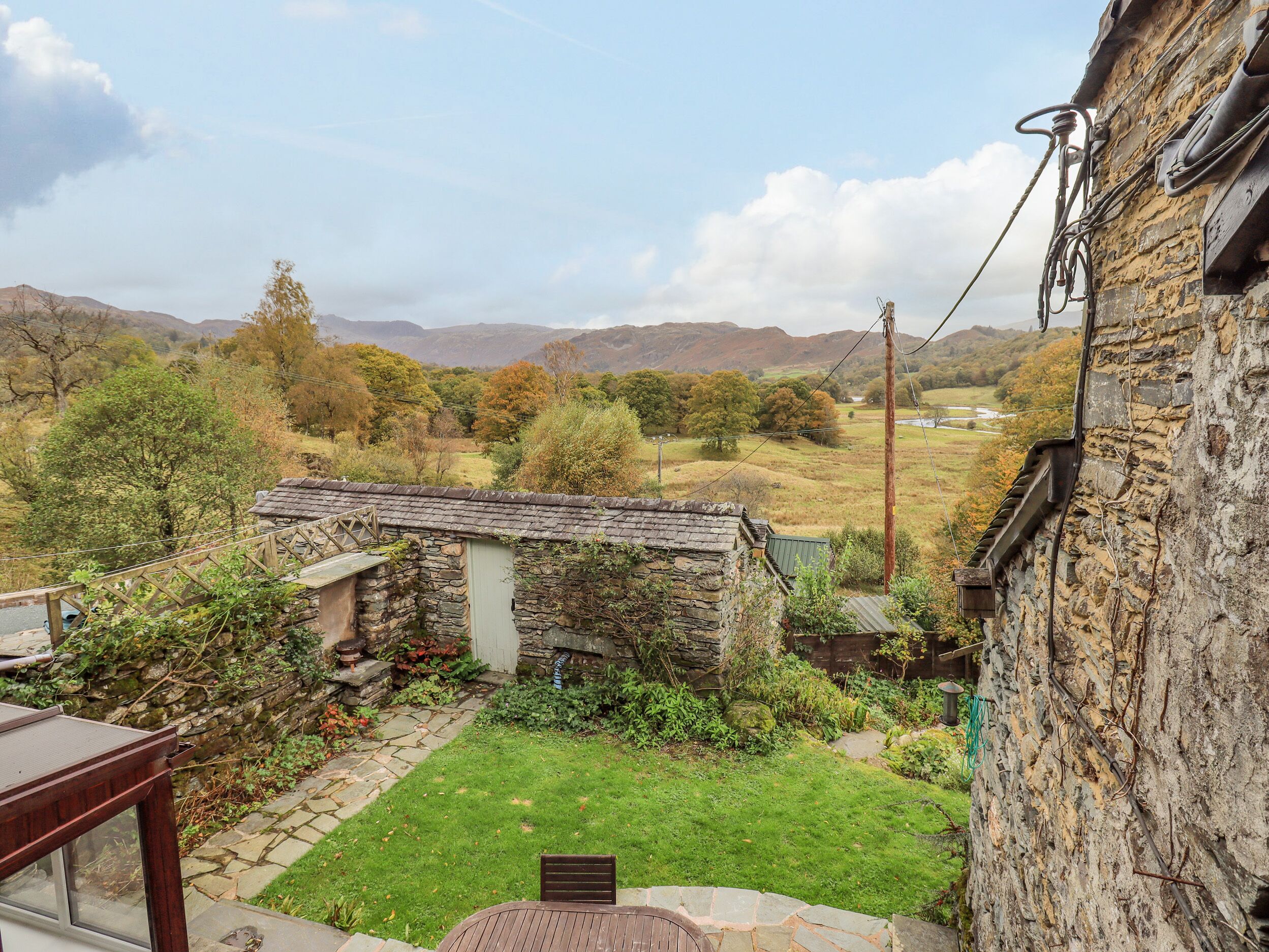 A stone house with a small garden and a view of the countryside.