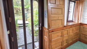 Ein Holzkabinent mit integriertem Fenster, einer Tür mit Spionglas und einer Steinwand.