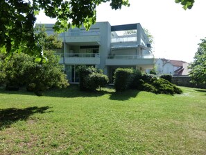 A modern two-story building with a flat roof, large windows, and a balcony.