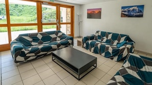 Quarto com dois sofás, uma mesa de centro e grandes janelas com vista para o verde.
