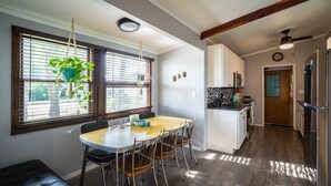 Une cuisine moderne avec un coin repas, un plancher en bois et une plante suspendue.