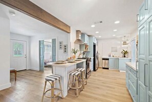 Une cuisine moderne dotée d’un îlot central, de tabourets de bar et d’un coin repas.