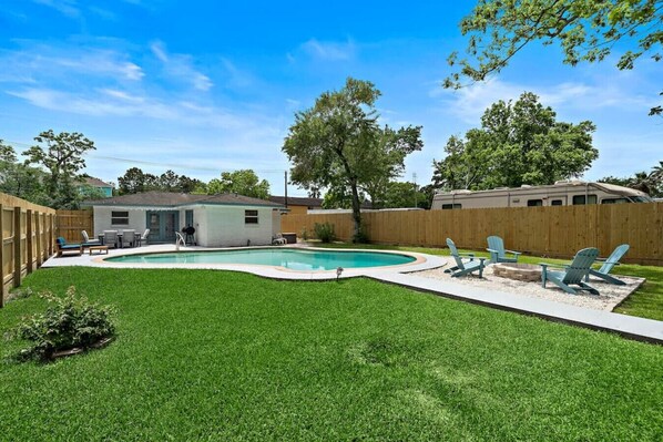 A backyard with a swimming pool, a small shed, and a wooden fence.