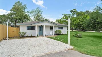A single-story mobile home with a front porch, a small lawn, and a wooden fence.