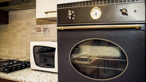 Una cocina con horno negro, microondas blanco y estufa a gas.