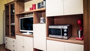 Eine Küche mit Holzausstattung, einer Mikrowelle, einem roten Mixer und einem Fernseher auf einem Holztisch.