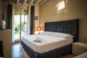 A bedroom with a large bed, a bedside table, a lamp, and a TV on a cabinet. - La Moderna Egman - Italian Homing (Sirmione)