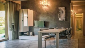 A modern dining area with a table and chairs, a television, and artwork on the wall. - La Moderna Egman - Italian Homing (Sirmione)