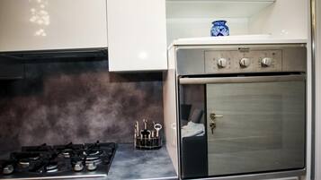Uma cozinha com fogão a gás, forno e um vaso azul na bancada.