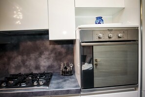 Una cocina con estufa a gas, horno y un florero azul en la encimera.