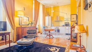 A living room with a leather chair, a dining table, and a kitchen area with a stove and cabinets. - Residenza Dei Signori - Italian Homing (Verona)