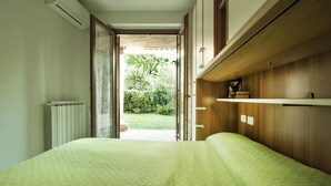 Un dormitorio con cama, radiador, armario de madera y vista a un jardín.