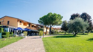 A courtyard with a stone pathway, outdoor seating, and a building with multiple windows and balconies. - La Casa sul Porto - Italian Homing (Sirmione)