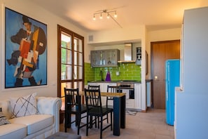 Un espace de vie compact comprenant un coin repas, une kitchenette et un grand tableau accroché au mur.
