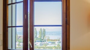 A room with a large sliding glass door leading to a balcony with a view of a marina and hills. - La Casa sul Porto - Italian Homing (Sirmione)