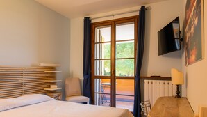 A bedroom with a bed, a chair, a table, a TV, and a view of the outdoors. - La Casa sul Porto - Italian Homing (Sirmione)